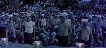 Movie still from “South Pacific” (1958), directed by Joshua Logan – A crowd of people in the dark with one man saluting; Wide shot, High angle
