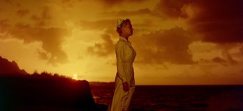 Movie still from “South Pacific” (1958), directed by Joshua Logan – A woman standing on the beach at sunset; Extreme Wide shot, Low angle