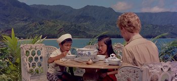 Movie still from “South Pacific” (1958), directed by Joshua Logan – Three children sitting at a table with bowls of food; Medium shot, High angle