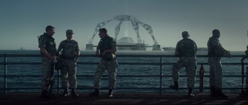Movie still from “Southland Tales” (2006), directed by Richard Kelly – A group of men standing on top of a pier; Wide shot, Low angle