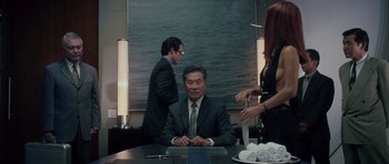 Movie still from “Southland Tales” (2006), directed by Richard Kelly – A man sitting at a table in front of two other people; Medium shot, Over the shoulder angle