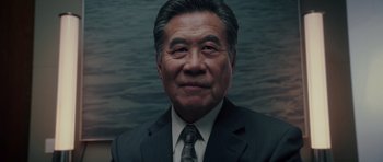 Movie still from “Southland Tales” (2006), directed by Richard Kelly – An older asian man in a suit and tie; Close Up shot, Low angle