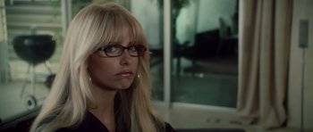 A woman with blonde hair wearing glasses and a black shirt