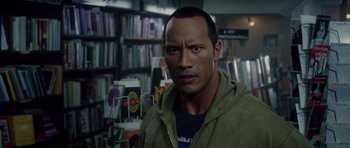 Movie still from “Southland Tales” (2006), directed by Richard Kelly – A man in a green jacket in front of a book shelf; Close Up shot, Over the shoulder angle