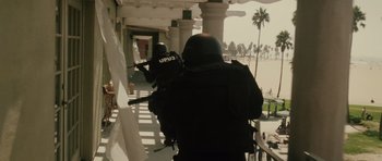 Two men in black uniforms are holding guns and standing on a balcony