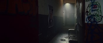 Movie still from “Southland Tales” (2006), directed by Richard Kelly – A dark room with a poster on the wall; Wide shot, High angle