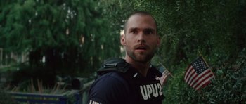 Movie still from “Southland Tales” (2006), directed by Richard Kelly – A man in a police uniform is looking at the camera; Close Up shot, Over the shoulder angle