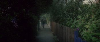 Movie still from “Southland Tales” (2006), directed by Richard Kelly – A person walking down a sidewalk holding an umbrella; Extreme Wide shot, High angle