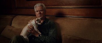 Movie still from “Southland Tales” (2006), directed by Richard Kelly – An older man sitting on a couch holding a dog; Close Up shot, High angle