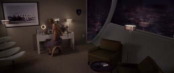 Movie still from “Southland Tales” (2006), directed by Richard Kelly – A woman sitting at a desk in front of a large window; Wide shot, High angle
