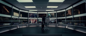 Movie still from “Southland Tales” (2006), directed by Richard Kelly – A person sitting in front of multiple monitors; Wide shot, Over the shoulder angle