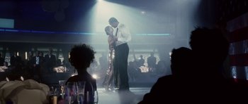 Movie still from “Southland Tales” (2006), directed by Richard Kelly – A man and a woman are dancing in front of a group of diners; Wide shot, Low angle