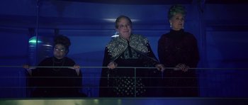 Movie still from “Southland Tales” (2006), directed by Richard Kelly – A woman in a black and silver dress standing next to a fence; Medium shot, Low angle