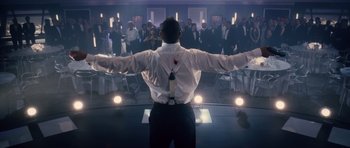 Movie still from “Southland Tales” (2006), directed by Richard Kelly – A man standing in front of an audience with his arms outstretched; Medium shot, Low angle