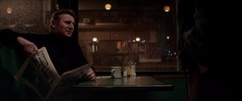 Movie still from “A Walk Among the Tombstones” (2014), directed by Scott Frank – A man sitting at a table with a cup of coffee; Medium shot, Over the shoulder angle