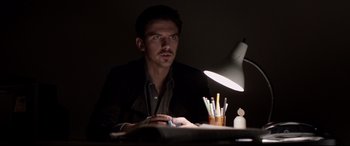 Movie still from “A Walk Among the Tombstones” (2014), directed by Scott Frank – A man sitting in front of a computer at a desk; Medium shot, Low angle