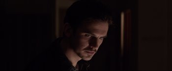 Movie still from “A Walk Among the Tombstones” (2014), directed by Scott Frank – A person in a dark room; Close Up shot, Over the shoulder angle