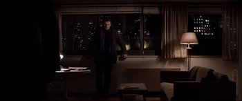 Movie still from “A Walk Among the Tombstones” (2014), directed by Scott Frank – A man standing in front of a window at night; Wide shot, Low angle