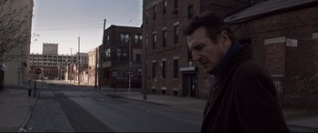 Movie still from “A Walk Among the Tombstones” (2014), directed by Scott Frank – A man standing on the side of the street; Medium shot, Low angle