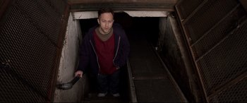 Movie still from “A Walk Among the Tombstones” (2014), directed by Scott Frank – A man standing in a tunnel looking at the camera; Medium shot, Overhead angle
