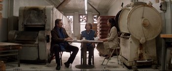 Movie still from “A Walk Among the Tombstones” (2014), directed by Scott Frank – A group of people sitting at a table in a room; Wide shot, Low angle