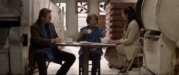 Movie still from “A Walk Among the Tombstones” (2014), directed by Scott Frank – A group of people sitting at a table drinking coffee; Medium shot, Over the shoulder angle