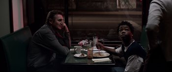 Movie still from “A Walk Among the Tombstones” (2014), directed by Scott Frank – Two men sitting at a table with food and drinks; Medium shot, Over the shoulder angle
