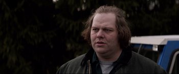 Movie still from “A Walk Among the Tombstones” (2014), directed by Scott Frank – A person wearing a jacket with trees in the background; Close Up shot, Over the shoulder angle