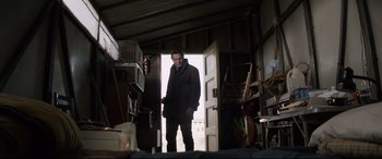 Movie still from “A Walk Among the Tombstones” (2014), directed by Scott Frank – A man standing in the doorway of a garage; Wide shot, Low angle