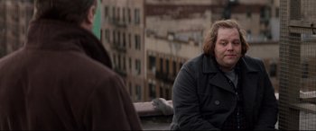 Movie still from “A Walk Among the Tombstones” (2014), directed by Scott Frank – A man sitting on top of a building next to another man; Medium shot, Over the shoulder angle
