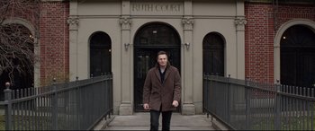 Movie still from “A Walk Among the Tombstones” (2014), directed by Scott Frank – A man standing in front of the entrance of a building; Wide shot, Low angle