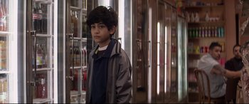 Movie still from “A Walk Among the Tombstones” (2014), directed by Scott Frank – A young boy standing in front of a store window; Close Up shot, Over the shoulder angle