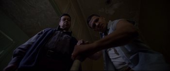 Movie still from “A Walk Among the Tombstones” (2014), directed by Scott Frank – Two men holding a baseball bat in a room; Medium shot, Low angle