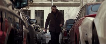 Movie still from “A Walk Among the Tombstones” (2014), directed by Scott Frank – A man walking down a street holding a cell phone; Wide shot, Low angle