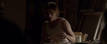 Movie still from “A Walk Among the Tombstones” (2014), directed by Scott Frank – A man in a white tank top holding a yellow object; Medium shot, Over the shoulder angle