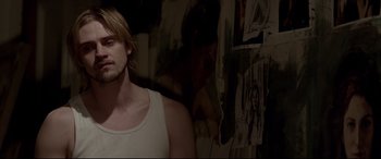 Movie still from “A Walk Among the Tombstones” (2014), directed by Scott Frank – A man with long blonde hair wearing a white tank top; Medium shot, Over the shoulder angle