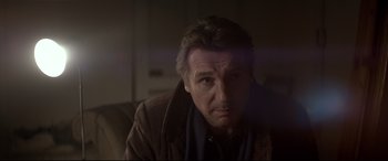 Movie still from “A Walk Among the Tombstones” (2014), directed by Scott Frank – A person sitting on a couch; Close Up shot, Over the shoulder angle