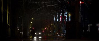 Movie still from “A Walk Among the Tombstones” (2014), directed by Scott Frank – A person walking down a street at night; Extreme Wide shot, Low angle