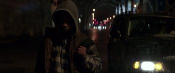 Movie still from “A Walk Among the Tombstones” (2014), directed by Scott Frank – A man in a hooded jacket walking down a street; Medium shot, High angle