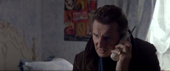 Movie still from “A Walk Among the Tombstones” (2014), directed by Scott Frank – A man talking on a phone while wearing a brown jacket; Close Up shot, High angle