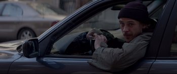 Movie still from “A Walk Among the Tombstones” (2014), directed by Scott Frank – A man sitting in the driver's seat of a car while using a cell phone; Medium shot, Over the shoulder angle