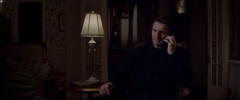 Movie still from “A Walk Among the Tombstones” (2014), directed by Scott Frank – A man sitting in a chair talking on a phone; Medium shot, High angle