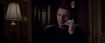 Movie still from “A Walk Among the Tombstones” (2014), directed by Scott Frank – A man talking on a cell phone while sitting in a chair; Close Up shot, High angle