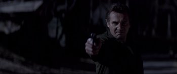 Movie still from “A Walk Among the Tombstones” (2014), directed by Scott Frank – A man holding a gun in a dark room; Close Up shot, Low angle