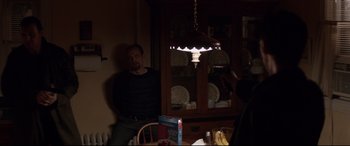 A man sitting at a dining room table in front of a china cabinet