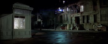 Movie still from “Soylent Green” (1973), directed by Richard Fleischer – A street corner at night with a street light and buildings; Wide shot, High angle