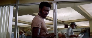 Movie still from “Soylent Green” (1973), directed by Richard Fleischer – A man in a tan shirt is standing in front of a mirror; Close Up shot, Low angle