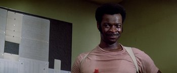 Movie still from “Soylent Green” (1973), directed by Richard Fleischer – A man in a pink shirt is smiling for the camera; Close Up shot, Low angle