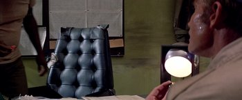 Movie still from “Soylent Green” (1973), directed by Richard Fleischer – A person sitting at a table in a room; Medium shot, Over the shoulder angle