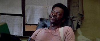 Movie still from “Soylent Green” (1973), directed by Richard Fleischer – A man sitting in a chair smiling at the camera; Close Up shot, High angle